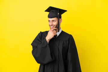 Young university graduate caucasian man isolated on yellow background looking to the side