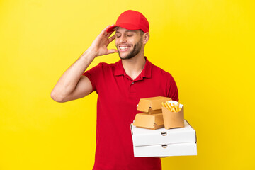 pizza delivery man picking up pizza boxes and burgers over isolated background smiling a lot