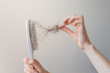 Female hand pulls out a clump of hair from a comb. Close-up. The concept of alopecia and hair loss