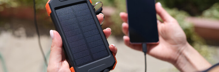 Female hand holding solar power bank and mobile phone closeup
