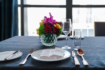 The western dining room is decorated with red wine glasses, white disks and silver-paper knives and forks.