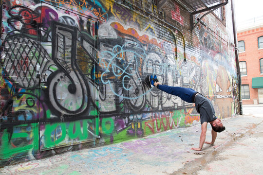 Flexible and strong male does back bend against a graffiti wall in Baltimore, Maryland