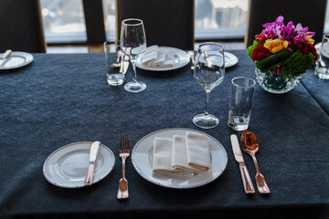 The western dining room is decorated with red wine glasses, white disks and silver-paper knives and forks.