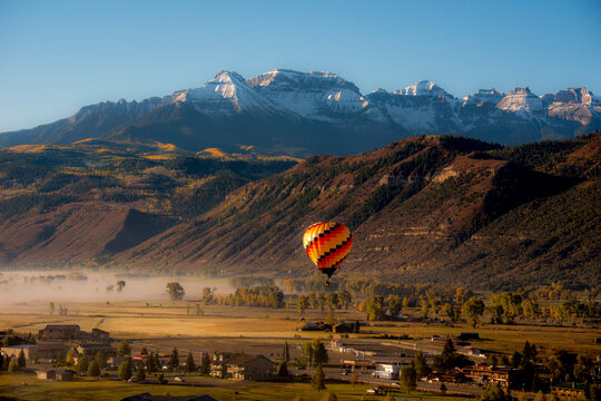 A hot air ballon over a small town with mountains in the background.  Ridgway, Colorado, USA.