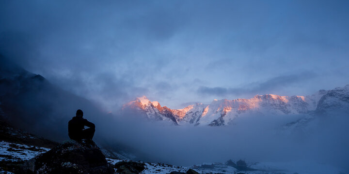A man looking out over sun lit mountain range. - Powered by Adobe