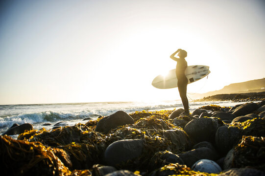 Surfer pulls on her wetsuit before paddling out