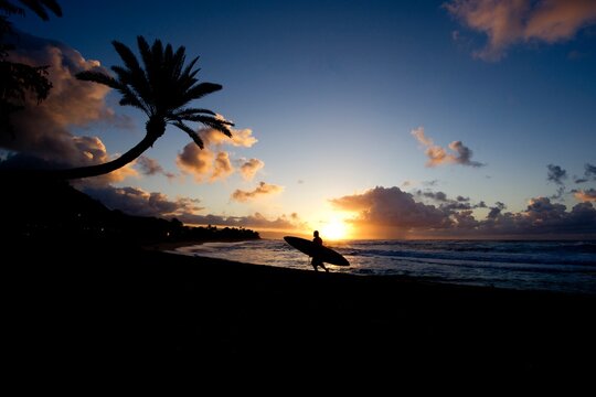 Surfer comes in at sunset