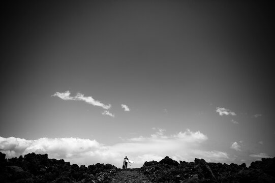Surfer crosses lava field to surf