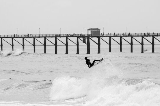 Surfer boosts air in front of pier