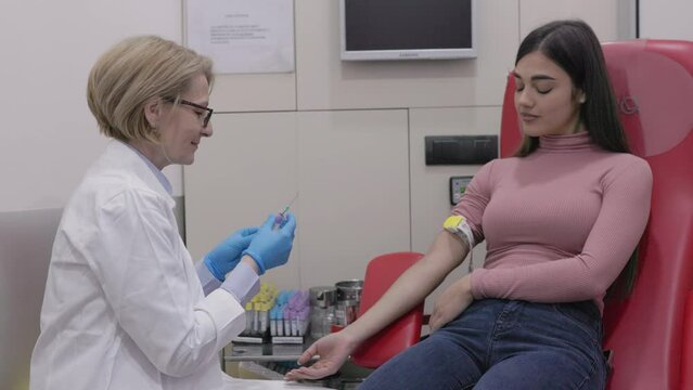 Preparation for blood test by female doctor medical uniform on the table in white bright room. Nurse pierces the patient's arm vein with needle blank tube.