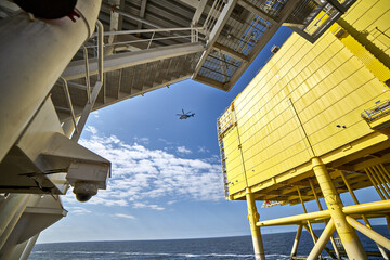 Divers support vessel working near offshore installation during helicopter operations. Helicopter in the sky.