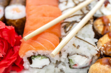 Wooden chopsticks on the tasty sushi rolls. Close up.