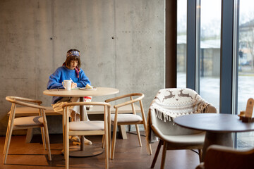 Young adult woman works on a digital tablet while sitting at modern coffee shop. Concept of remote creative work online