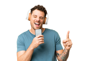 Brazilian man over isolated chroma key background listening music with a mobile and singing