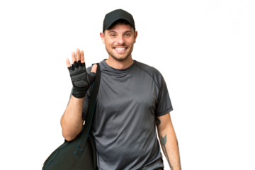 Young sport man with sport bag over isolated chroma key background saluting with hand with happy expression