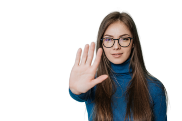 Stop! Stay away! A young European girl in a dark blue jumper and pants put her hand in front of her in a stopping gesture, standing on transparent background..Student trying to avoid bullying.