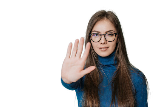 Stop! Stay away! A young European girl in a dark blue jumper and pants put her hand in front of her in a stopping gesture, standing on transparent background..Student trying to avoid bullying.