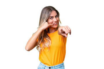 Young Uruguayan woman over isolated background making phone gesture and pointing front