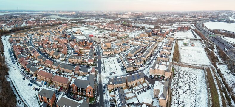 Aerial drone. Ebbsfleet garden city in Kent, covered in snow in December 2022. Aerial view of new developments and frozen lake alongside the A2 motorway.