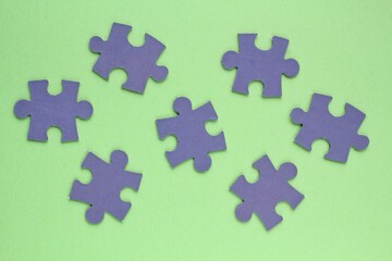 Violet mosaic game details of jigsaw puzzle elements on green background. Completing task or solving problem concept. World mental health day, autism awareness day. Global communication. Hobby, play