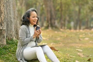 Elegant elderly woman drinking coffee and enjoy outdoor leisure activity on a warm day. Authentic...
