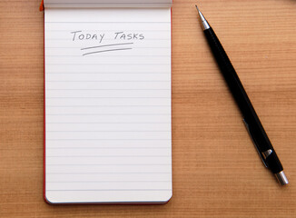 Today Tasks text hand written with a pencil on a notepad to encourage daily planning and organization. View from top