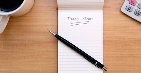 Today Tasks text hand written with a pencil on a notepad to encourage daily planning and organization. View from top