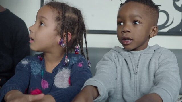 happy african american little kids playing outdoors a sunny day in cold weather wearing winter fashion and beanie knit hats with earflaps