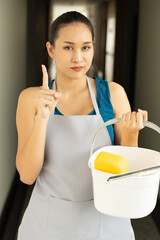 Confident professional Asian cleaning service worker woman pointing up, concept image of domestic...