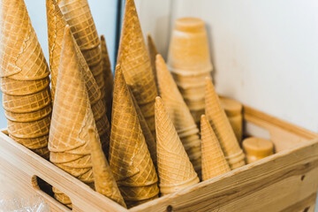 Closeup of stack of empty waffle ice cream cones in an Ice cream shop in wooden container. High quality photo