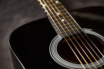 Guitar black, polished smooth soundboard, stretched six strings, copper frets on neck, close-up...
