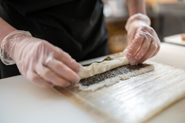 Obraz premium professional chef's hands making sushi and rolls in a restaurant kitchen