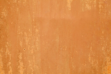 Roughly painted with orange paint metal surface, background wallpaper, uniform texture pattern