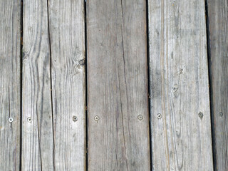 An ancient wooden background with peeling paint. The boards are grey. The boards are arranged in parallel. Texture. Background.
