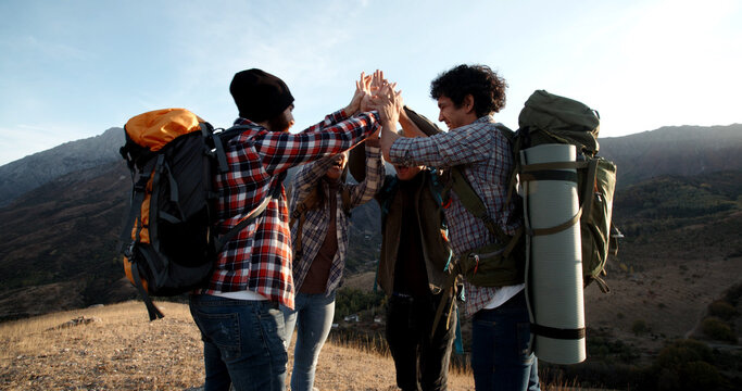 Students on hike adventure - Four young authentic people cheering on top of mountain, doing a highfive, expressing positive emotions - friendship, travel destination - Powered by Adobe