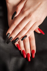 Hands of a young girl with black and red manicure on nails