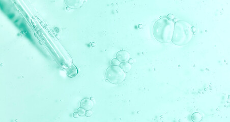 Cosmetic serum texture with dropper transparent liquid green background