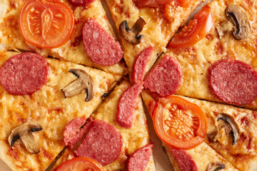 Top view closeup of pizza slice with onions, sausage and cherry tomatoes, thin pastry crust, junk food, fast food.
