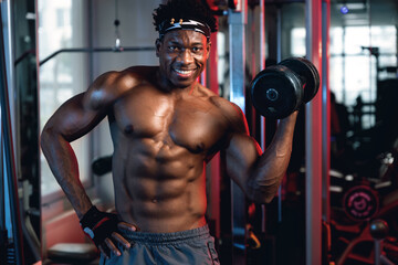 20s Black and muscular man in a gym doing biceps curl with dumbbell