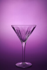 Elegant empty martini glass on purple background