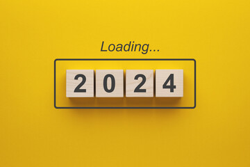 2024 new year loading. Wooden cubes with 2024 on a yellow background.