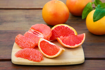 Fototapeta na wymiar Cut and whole fresh ripe grapefruits on wooden table