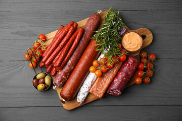 Different types of tasty sausages on grey wooden table, flat lay