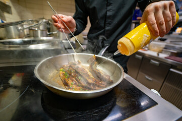 man chef cooking fried meat slice in frying pan on restaurant kitchen
