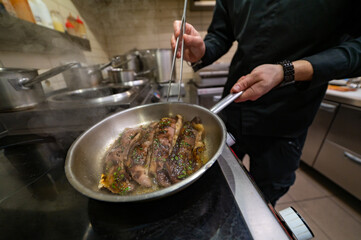 man chef cooking fried meat slice in frying pan on restaurant kitchen
