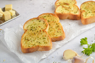 Tasty bread with garlic, cheese and herbs on kitchen table
