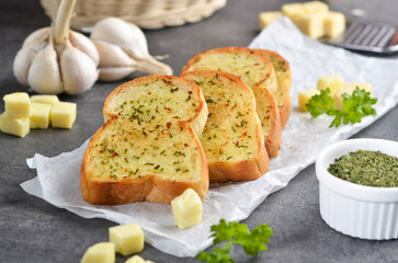 Tasty bread with garlic, cheese and herbs on kitchen table

