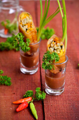 An Indonesian traditional snacks loempia or lumpia eaten with brown sauce, chili and onion  isolated on wood table
