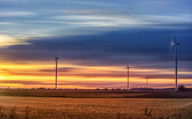 Fototapeta na wymiar Windmill in Nature. Blurry Cloudy Sky. Long Exposure. Beautiful Nature. Sunset Light.