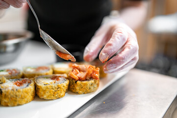 professional chef's hands making sushi and rolls in a restaurant kitchen